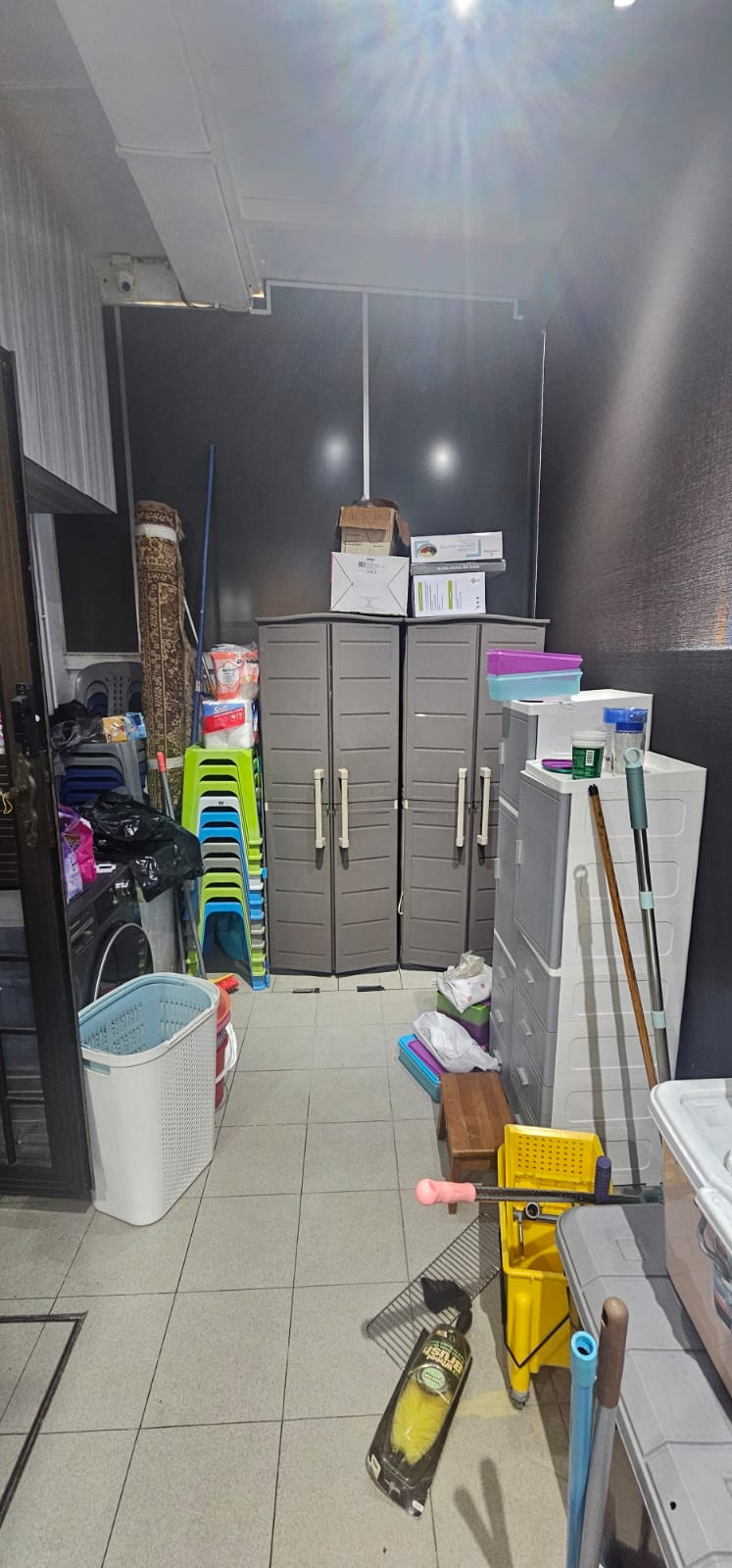 Before: Cluttered HDB storeroom with portable cabinets and cleaning items