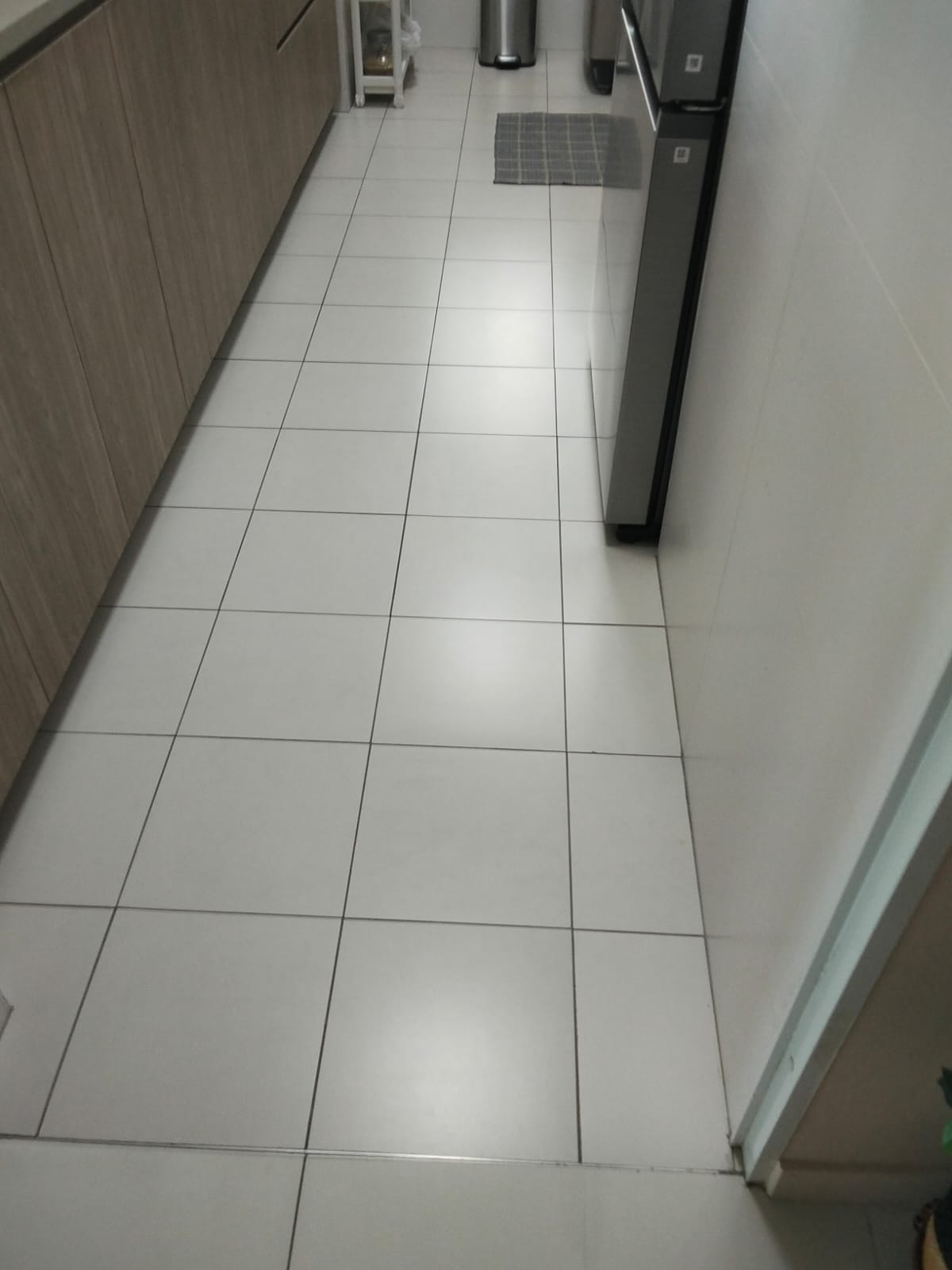 Before: HDB kitchen floor with dark stained grout lines between white tiles