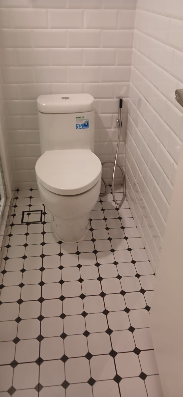 After: New white subway wall tiles, black and white octagonal floor tiles, new Kohler toilet