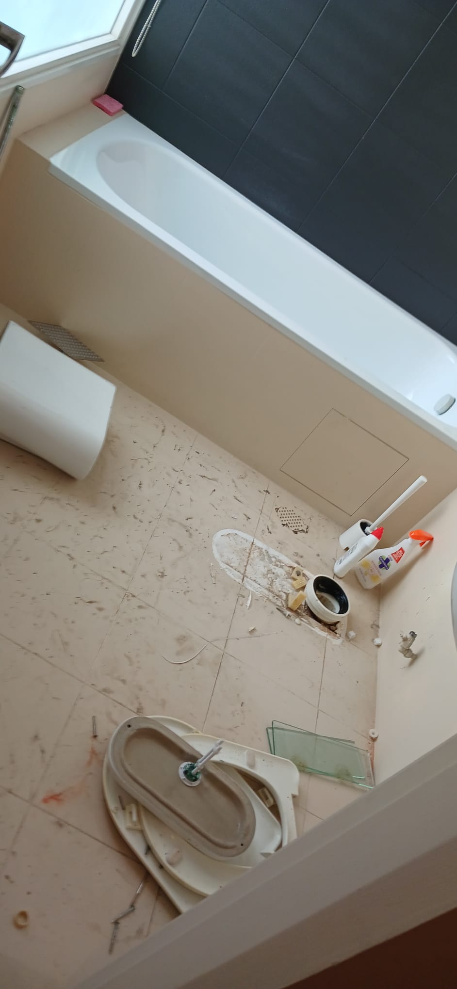 Before: Condo bathroom with bathtub, toilet removed, dirty floor during renovation